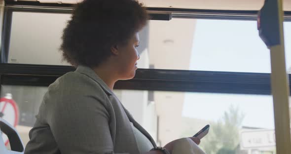 Happy plus size biracial woman using smartphone in bus