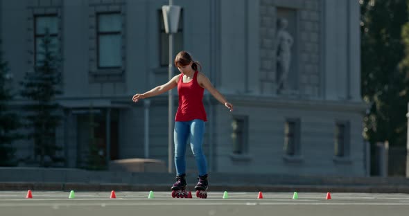 Girl Teenager Trains on Roller Skates Goes Around the Cones on the Site