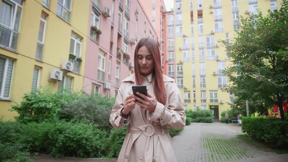 Woman Walking and Using Her Smart Phone in City