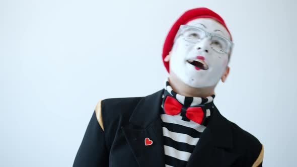Shy Mime Artist in Colorful Clothes and Eyeglasses Laughing Covering Mouth with Hand Looking at