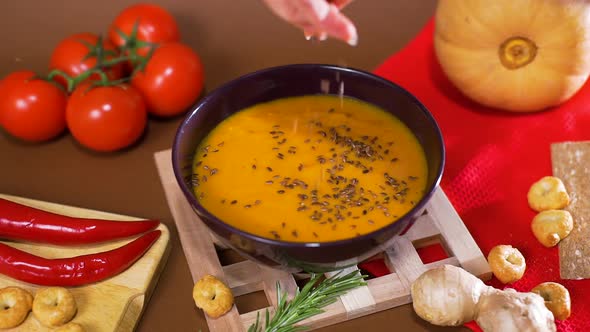 Female Adding Spices and Rosemary To Pumpkin Soup