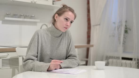 Young Woman Thinking and Writing on Paper at Home