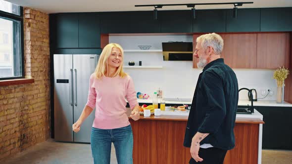 Happy Middle Aged Near 50s Family Couple Having Fun Cooking Together