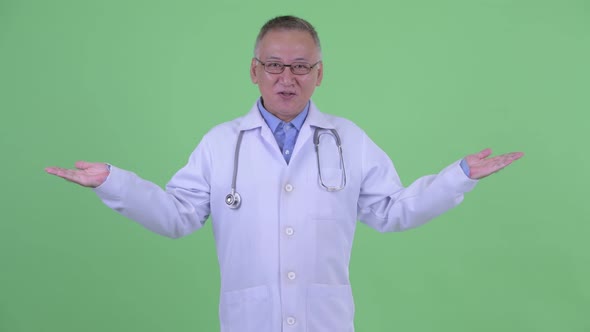 Happy Mature Japanese Man Doctor Explaining and Comparing Something