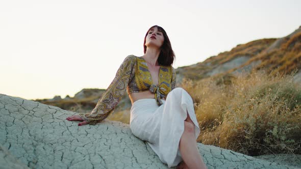 Young Model Poses on the Rock in the Mountains in Summer