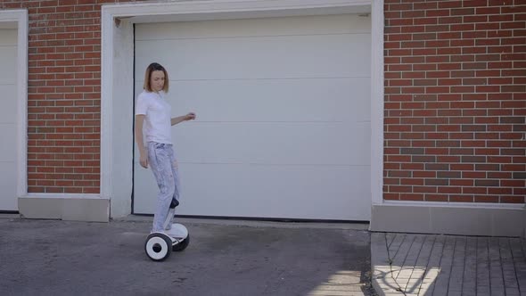 A Slender Young Girl Rides a Gyro Scooter Along a City Street. Modern Electric Transport.