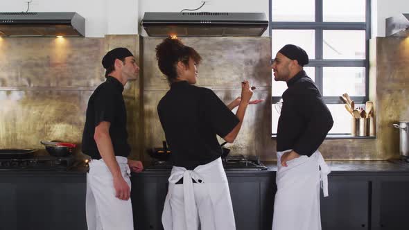 Diverse group of chefs preparing a dish and smiling in a kitchen