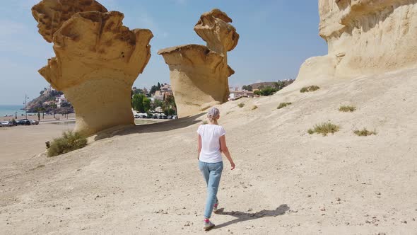 Girl Walking Through the Desert Near Yellow Futuristic Rock