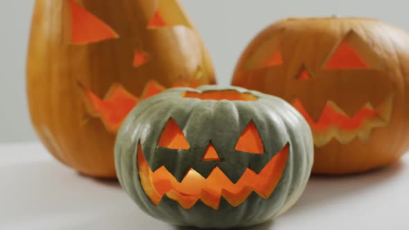 Close up view of multiple scary face carved halloween pumpkin against grey background