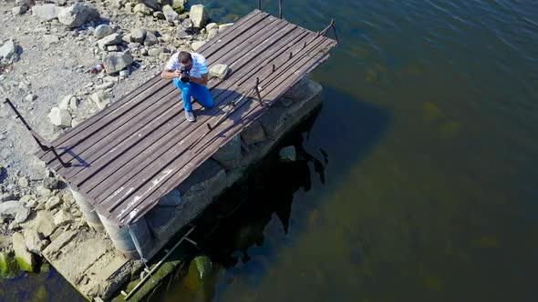 Man Taking Photos Near Pond