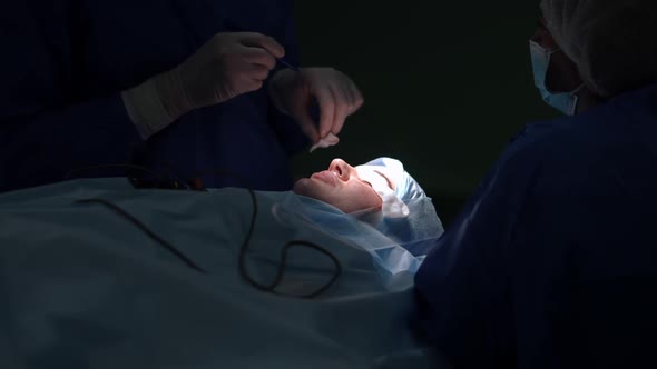 Plastic Surgeon Checking Pen Marking Dissection on Eyelid of Young Woman Lying on Surgery Bed