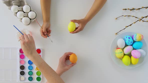 Hands of Child and Parent Coloring Easter Eggs