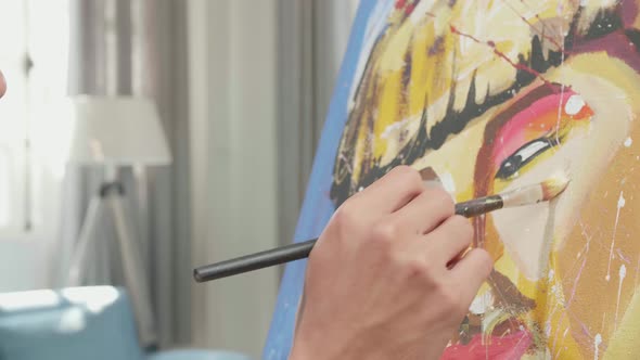 Close Up Side View Of An Asian Artist Man Painting A Girl's Face On The Canvas