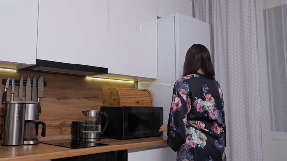 Woman in Gown Sneaks Up to Large Refrigerator to Take Cake