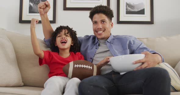 Happy biracial man and his son watching american football match together