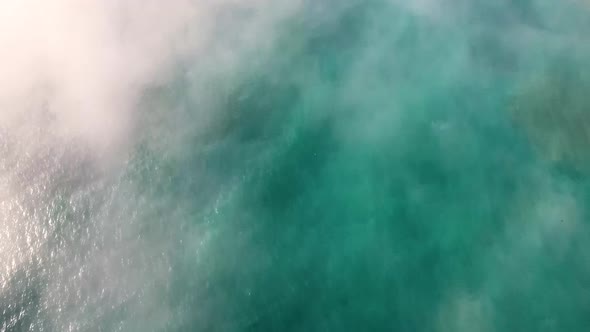 AERIAL: Beautiful blue ocean can be seen through the fog as we tilt up to reveal an Oregon coastline