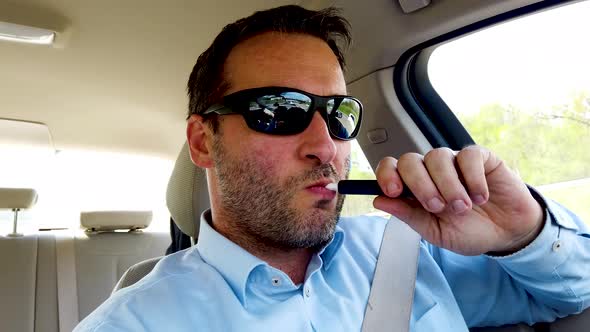 Man driving along a highway while using Iqos