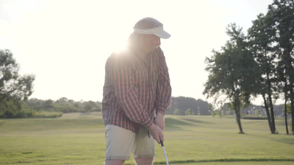 Portrait Successful Mature Golfer Swinging and Hitting Golf Ball on Beautiful Course