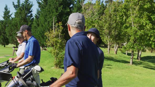 Senior people walking with their golf bags at golf course on a bright sunny day