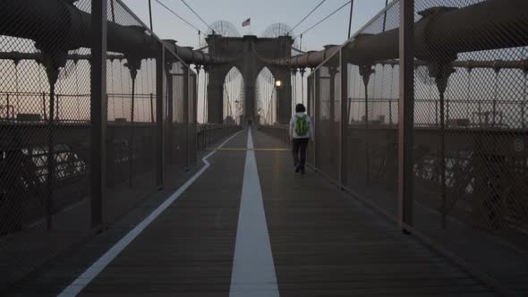 Brooklyn Bridge with Woman Walking Early Morning at Sunrise in Beautiful Sunlight in Summer 