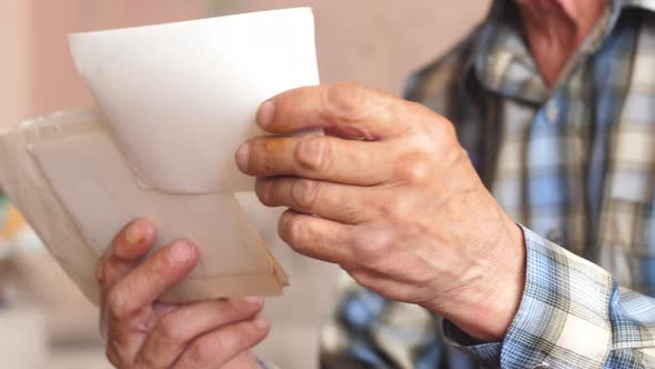 close-up of the hand of an elderly man holding old family photos. a pensioner remembers the past whi