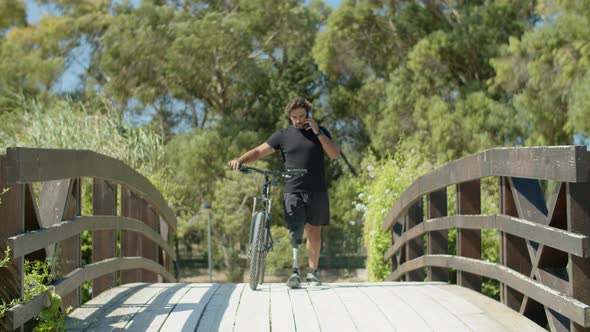 Front View of Man with Bionic Leg Answering Call During Cycling