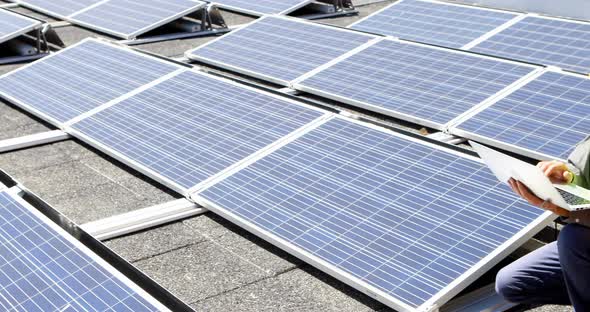 Male worker using laptop at solar station