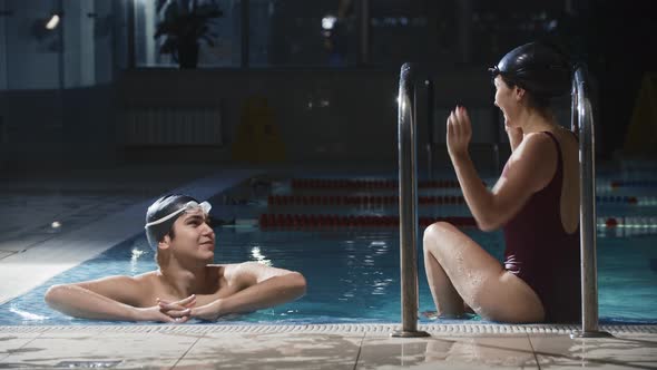 Swimming Sports  Young Man and Woman Swimmers Talking By a Swimming Pool Then Continue the Training