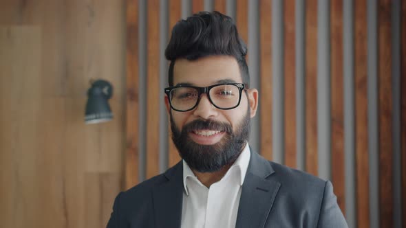 Portrait of Handsome Middle Eastern Man Wearing Glasses and Suit Standing Indoors Smiling