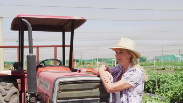 Video of happy caucasian woman standing in front of tractor