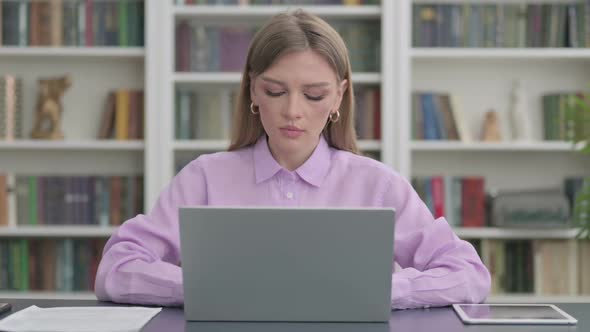 Woman Looking at Camera While Using Laptop in Office