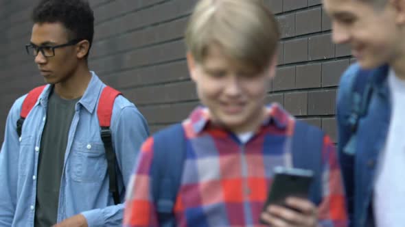 Caucasian Schoolboys Mocking Afro-American Guy Writing Comments in Social Net