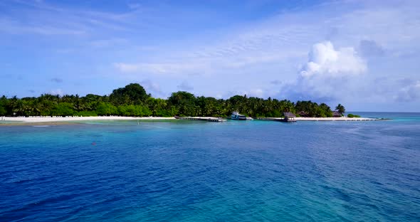 Tropical flying clean view of a white sandy paradise beach and blue water background in vibrant 4K