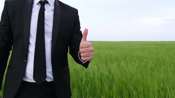 A Man in a Black Suit Shows a Thumb Up a Sign of Pleasure