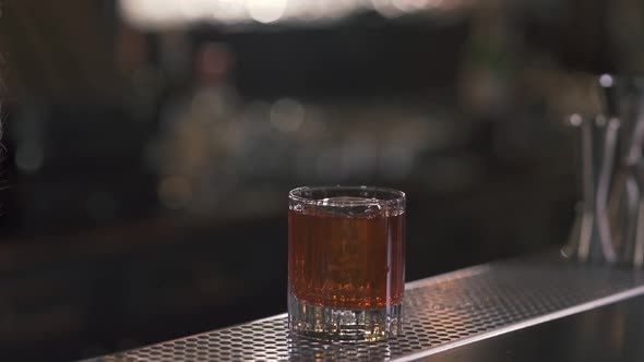 A Glass of Whiskey or Another Alcoholic Drink with Ice Stands on the Bar Counter