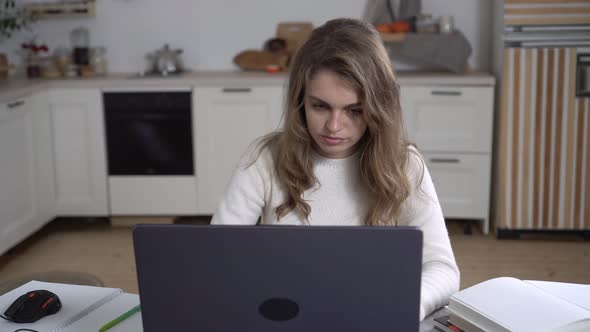 A Young Woman Works at Home with a Laptop