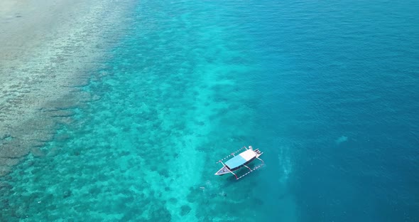 Tropical island, boat in turquoise water over beautiful coral reef, aerial