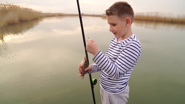 Boys Caughts a Small Fish on a Fishing Rod