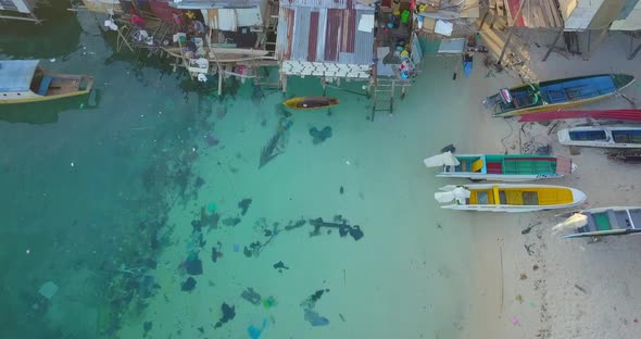 Aerial flight over clear ocean towards beach huts at sunset in Mabul, Malaysia