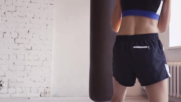 Beautiful Kickboxing Woman Training Punching Bag in Fitness Studio