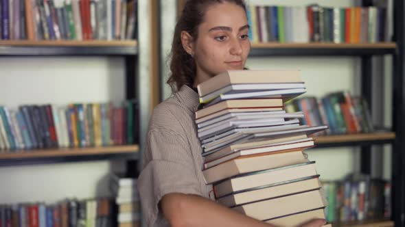 Girl Student Holding a Lot of Books in the Library Preparing for Exams