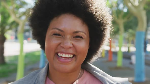 Portrait of happy plus size biracial woman smiling in park