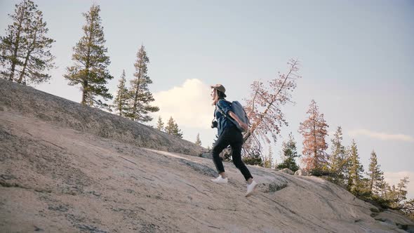 Young Beautiful Female Tourist with Backpack Hiking Alone, Climbing a Giant Rock at Yosemite