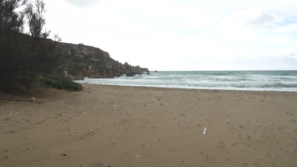 Slowly Walking On Sandy Golden Bay Beach on Cloudy Day with Roaring Mediterranean Sea in Malta