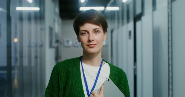 A Businesswoman with a Tablet Smiling Looking Into Camera in the Office