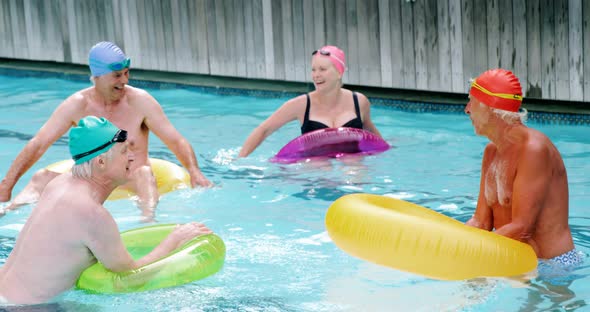 Seniors with inflatable tubes enjoying in pool