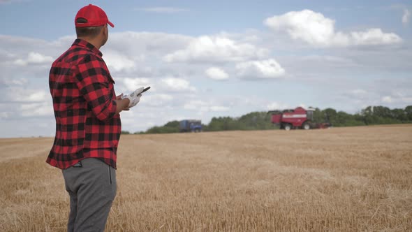 Agronomist Young Man Using Smartphone in Agriculture Farm. Farmer with Mobile Phone in a Wheat Field