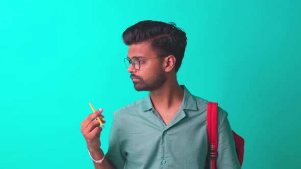 Indian Student Man Feeling Inspiration Idea Wear Eye Glasses Holding a Pencil in Blue Studi