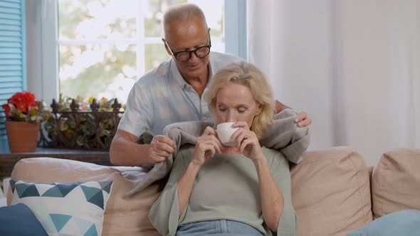 Mature Man Covering Happy Woman with Blanket at Home