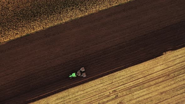 Aerial top view shot of Agricultural machine driving in brown fields